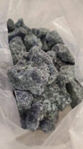 Hand holding MDMA crystals with UK and EU flags in the background